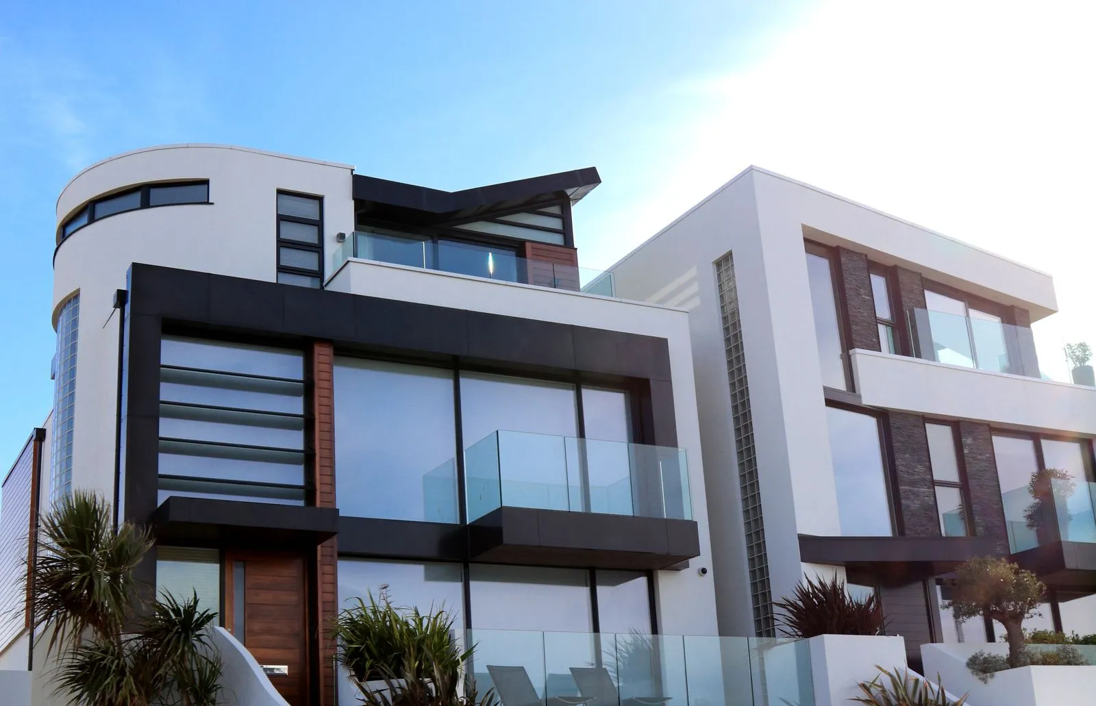 Fachada contemporánea de vivienda blanca con carpintería en madera y piedra.