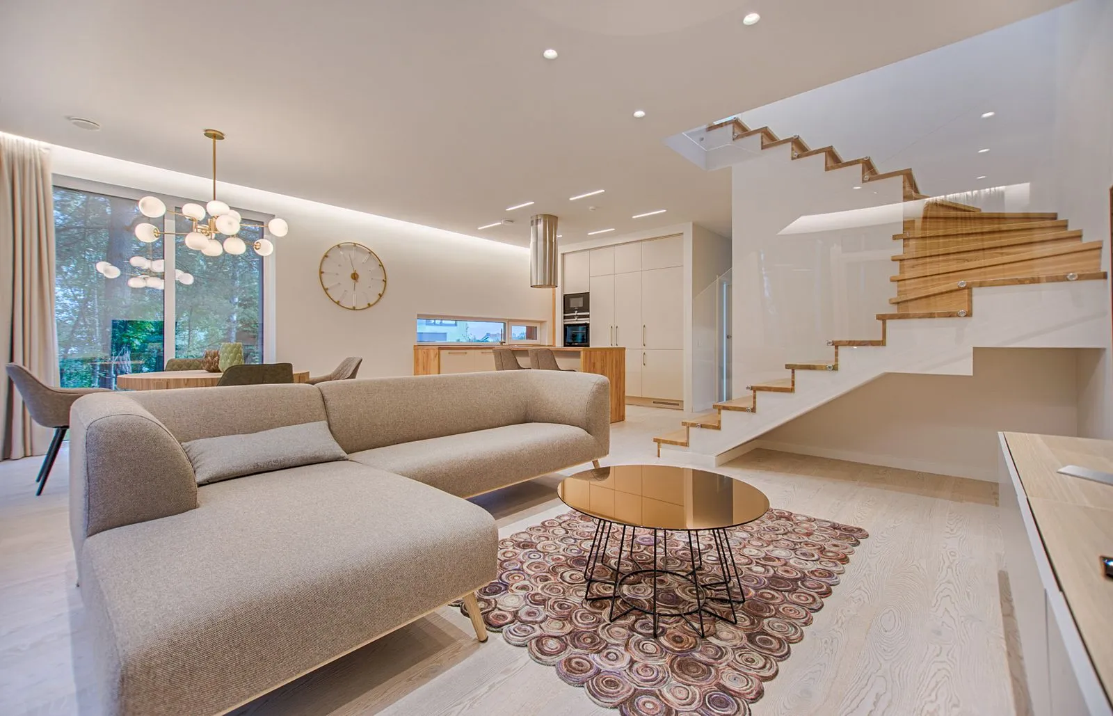 Interior de loft con escalera de vidrio, cocina abierta y paleta en tonos cálidos.
